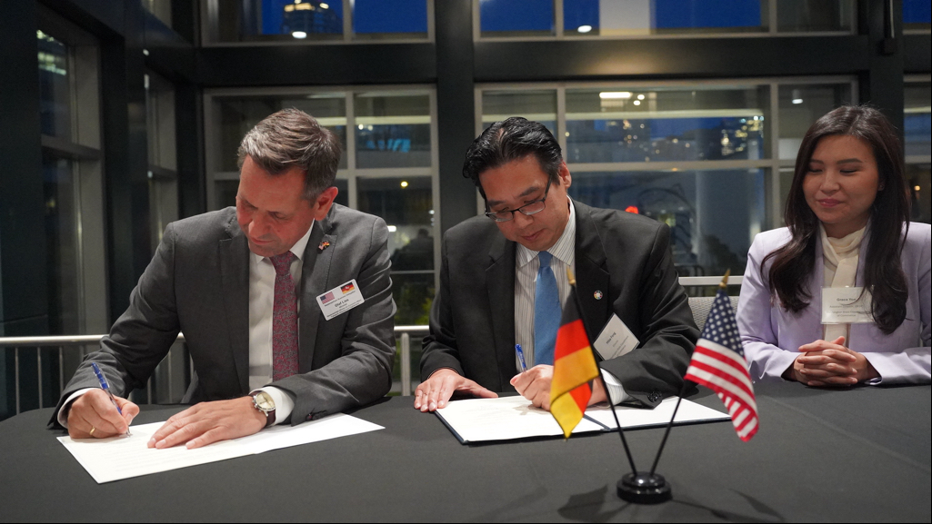 Olaf Lies, Minister of Economic Affairs, Transport, Building, and Digitalization for Lower Saxony, and Washington State Commerce Director Mike Fong sign a memorandum of understanding last night in Seattle. Commerce Assistant Director for Economic Development and Competitiveness Grace Yoo looks on.