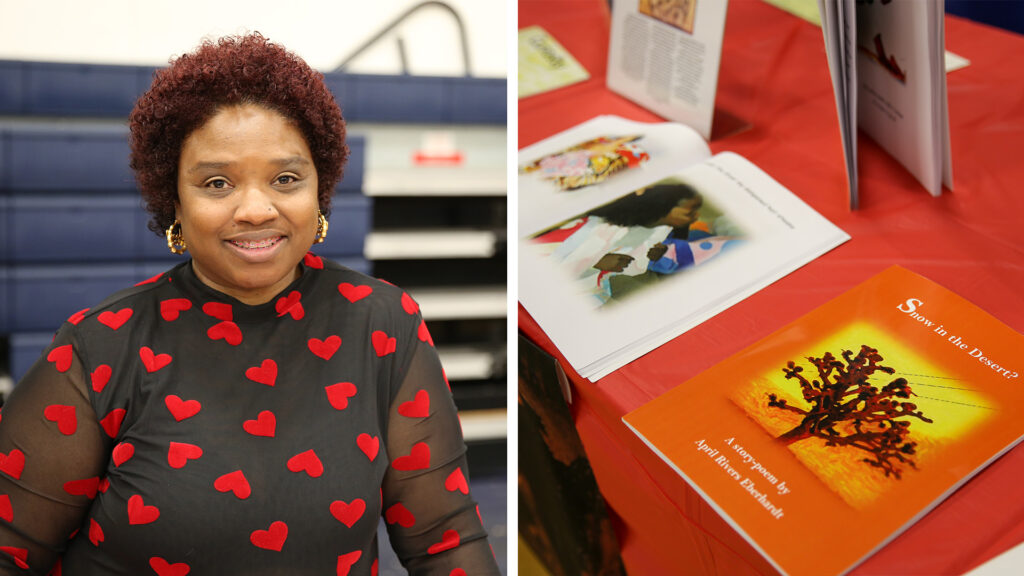  April Rivers Eberhard poses in front of collapsed gymnasium bleachers. Three of her books are on display on a red tablecloth, laying closed or open, and one standing up. 