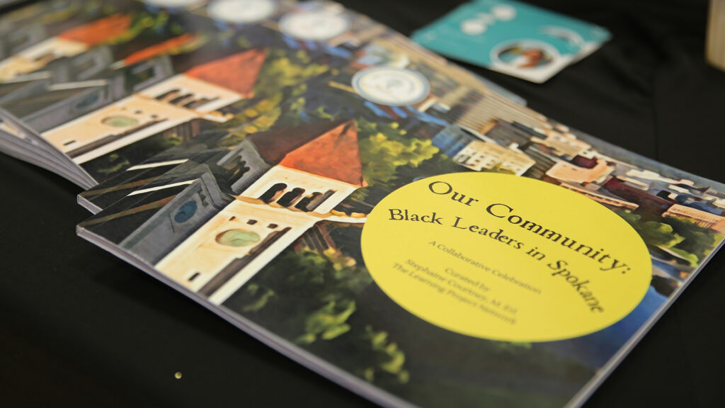 The book, "Our Community: Black Leaders in Spokane" is displayed on a black tablecloth. 