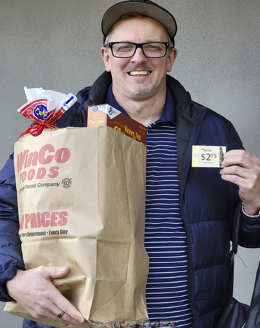 A man holding a bag of groceries and a transit card.