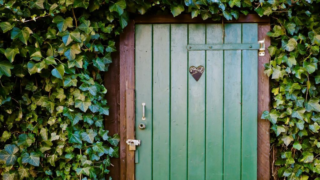 Green door with a heart surrounded by green plants